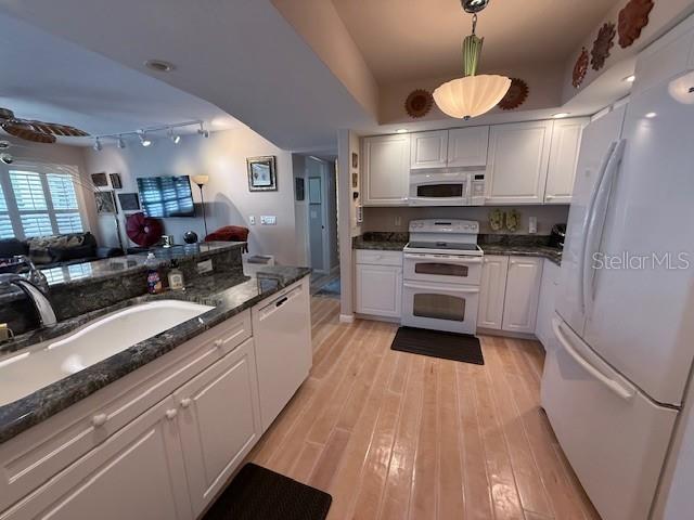A kitchen features white cabinets, dark countertops, light wood flooring, and a white refrigerator — 3806 GULF OF MEXICO DRIVE UNIT C108, LONGBOAT KEY, FL