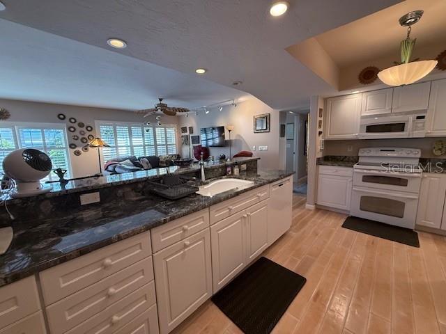 A kitchen features white cabinetry, dark granite countertops, and light wood flooring — 3806 GULF OF MEXICO DRIVE UNIT C108, LONGBOAT KEY, FL