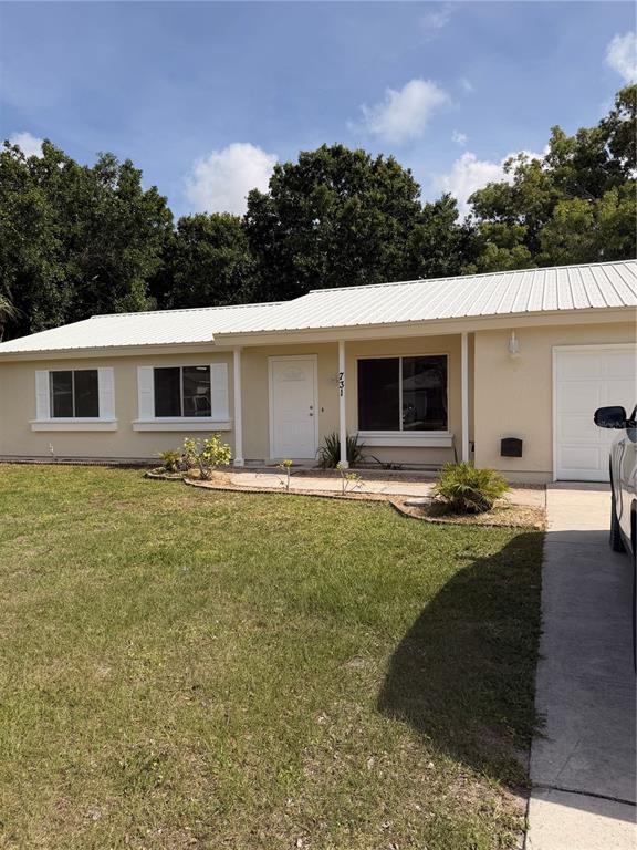 A single-story house with a white metal roof, light-colored siding, and a concrete driveway — 731 SW 24TH STREET, VERO BEACH, FL