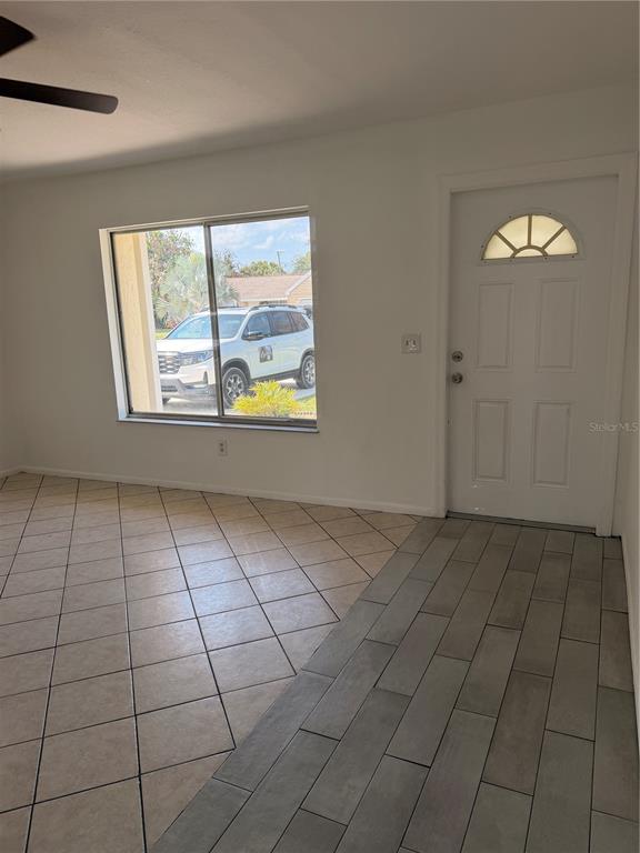 A room with a white front door, a large window, and two different tile floors — 731 SW 24TH STREET, VERO BEACH, FL