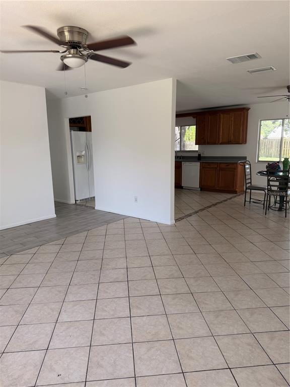 An open-concept living area features tile flooring, a ceiling fan, and an adjacent kitchen — 731 SW 24TH STREET, VERO BEACH, FL
