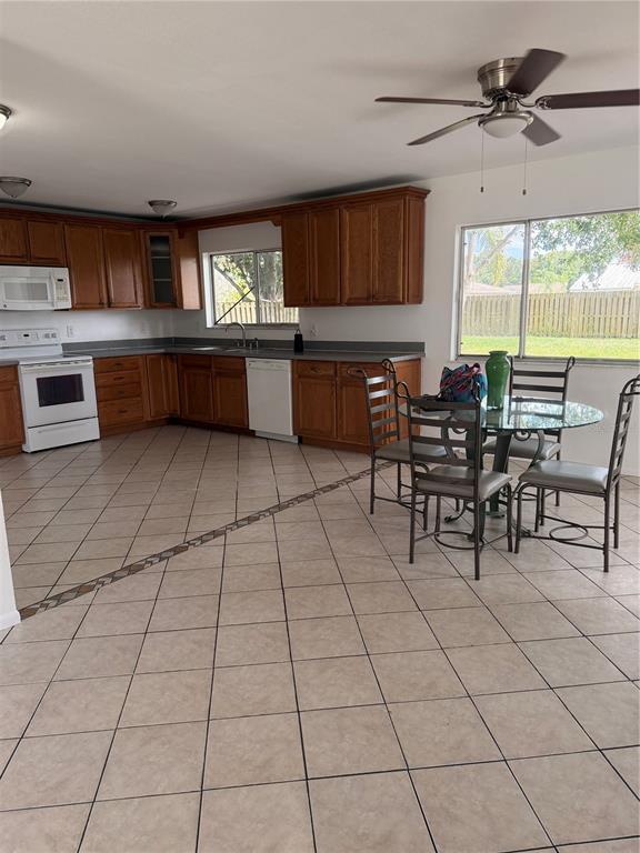 A kitchen with wood cabinets, tile flooring, and a dining table near a large window — 731 SW 24TH STREET, VERO BEACH, FL