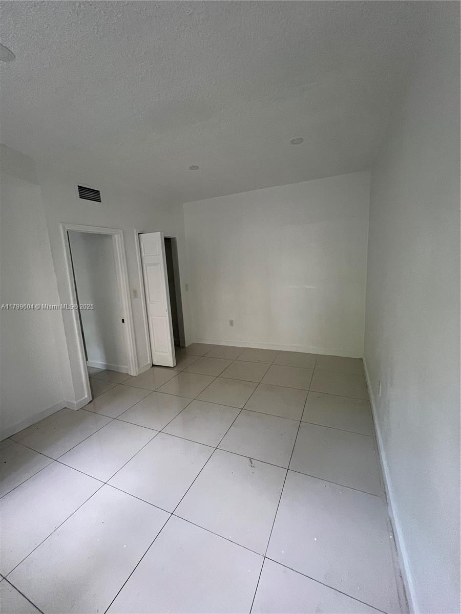 An empty room features white walls, a doorway, a closet, and light-colored tile flooring — 2345 NW Flagler Ter # 1, Miami FL 33125, MIAMI, FL