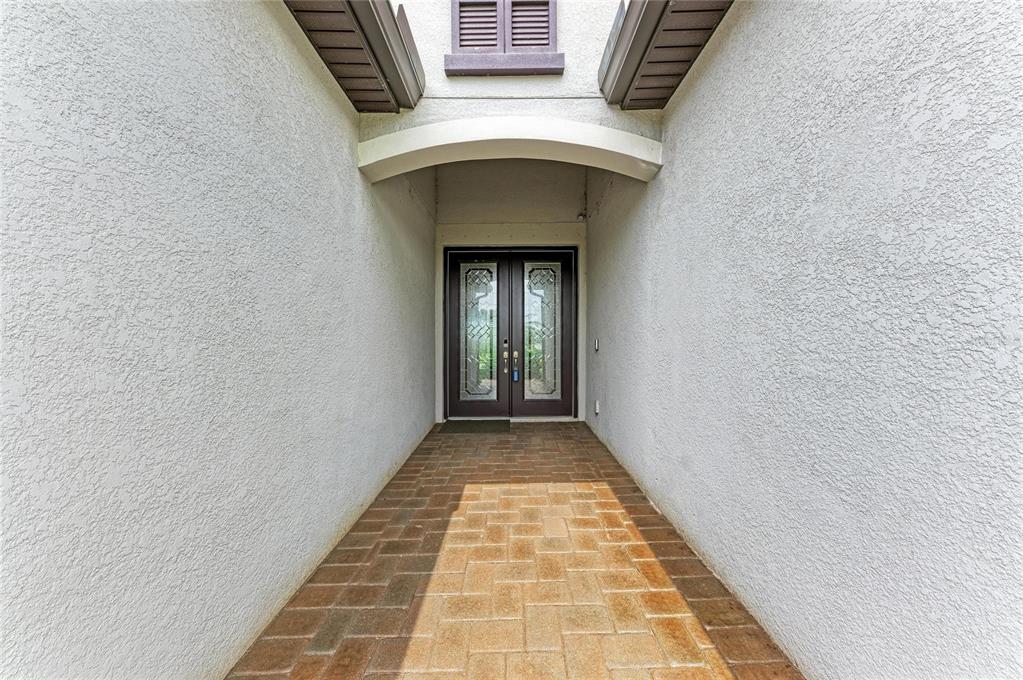 A covered entryway features a brick paver walkway leading to a dark double front door — 538 FIRE BUSH COURT, BRADENTON, FL