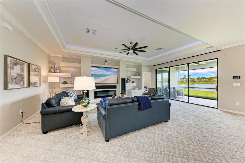A living room features dark leather sofas, a fireplace, built-in shelving, and sliding glass doors — 538 FIRE BUSH COURT, BRADENTON, FL
