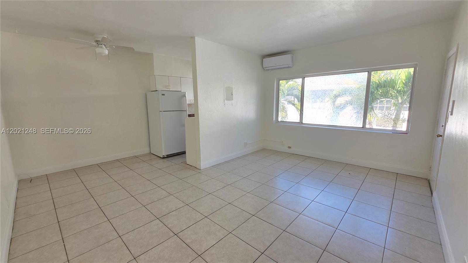An open living area features white walls, tiled floors, a ceiling fan, and a refrigerator — 7629 Dickens Ave # 7, Miami Beach FL 33141, MIAMI BEACH, FL