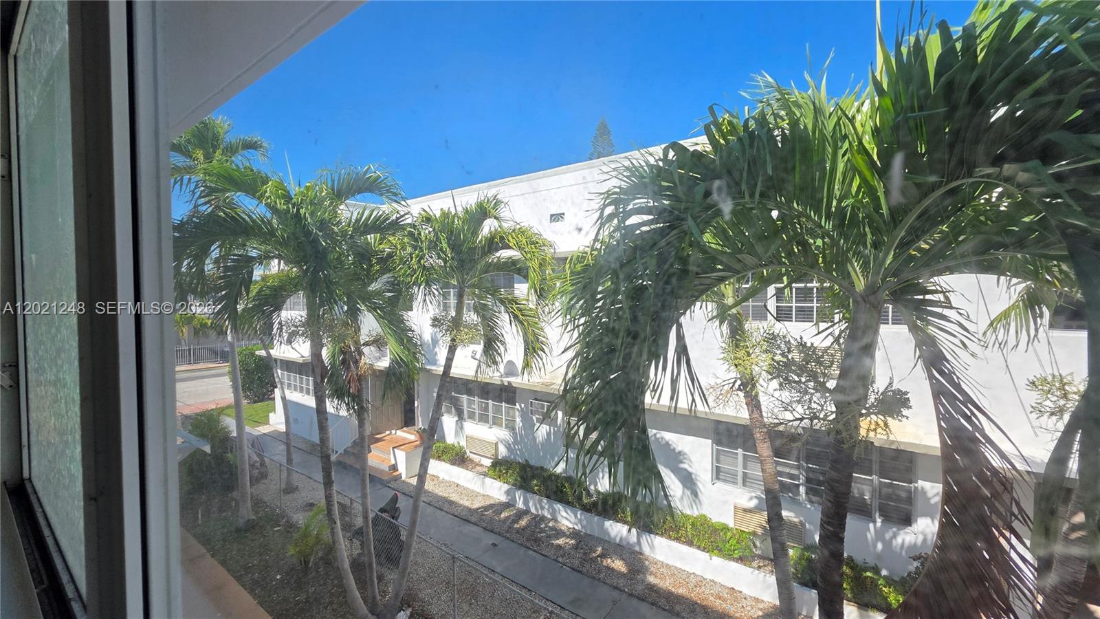 A kitchen with white appliances and tile flooring opens into a bright living area — 7629 Dickens Ave # 7, Miami Beach FL 33141, MIAMI BEACH, FL