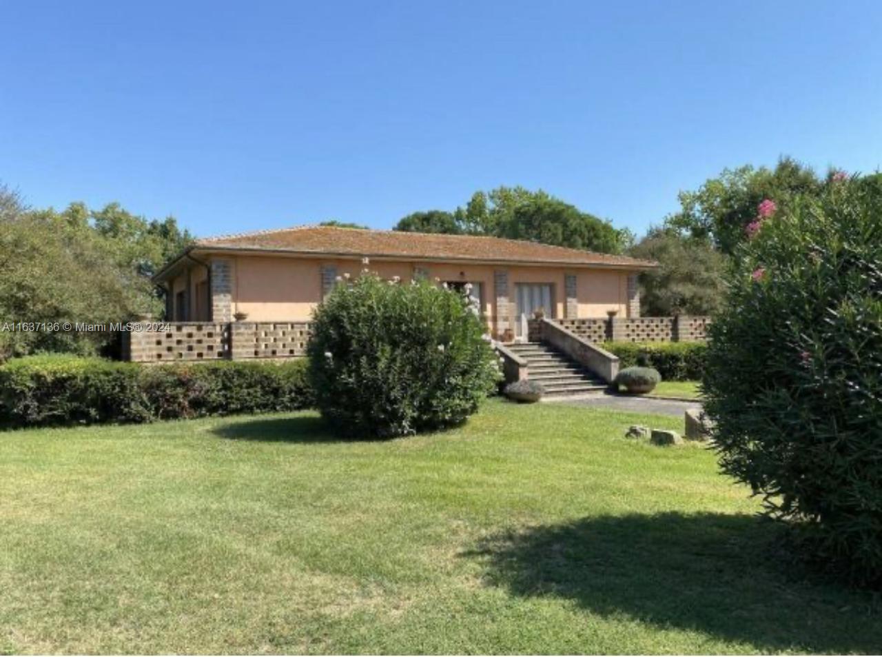 A single-story house with a low-pitched roof sits behind a low stone wall and lawn — 4 NW Via tiberina, 00100, FL