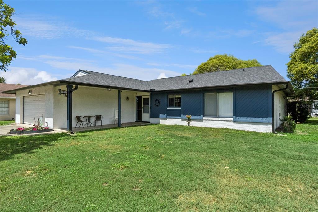 A single-story house with a white stucco facade, blue siding, and a covered front porch — 10044 GARRISON LANE, ORLANDO, FL