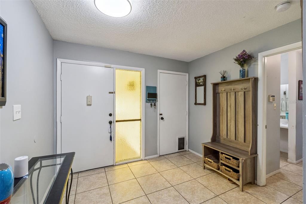 An entryway features tile flooring, a coat rack bench, and two white doors — 10044 GARRISON LANE, ORLANDO, FL