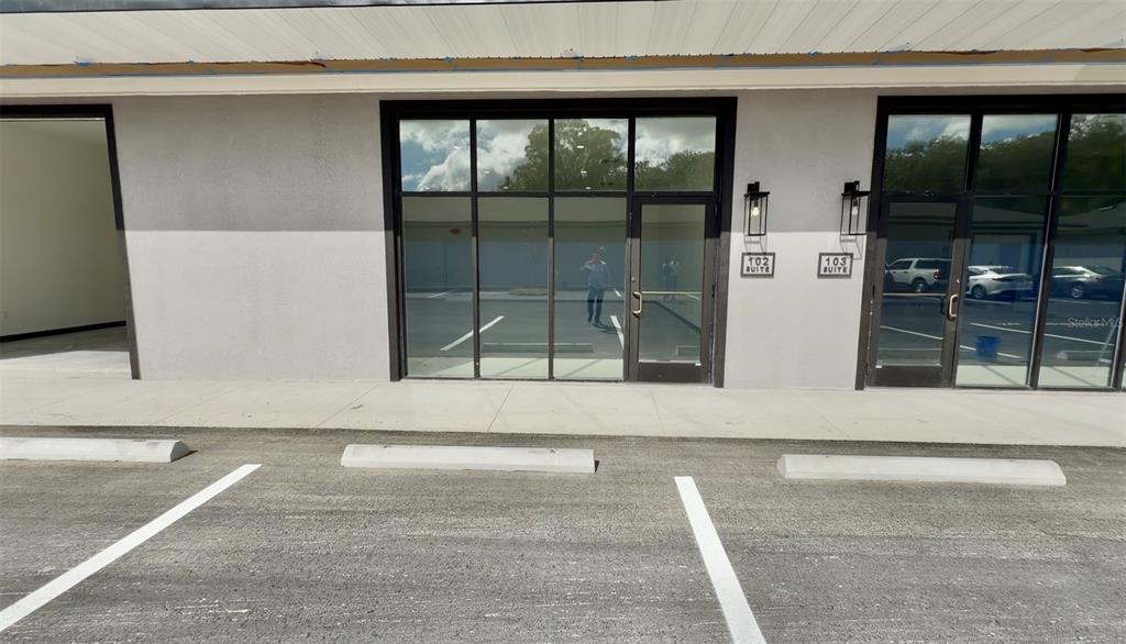 An exterior view of a commercial building with glass storefronts and a paved parking lot — 727 TILLMAN PLACE UNIT 102, PLANT CITY, FL
