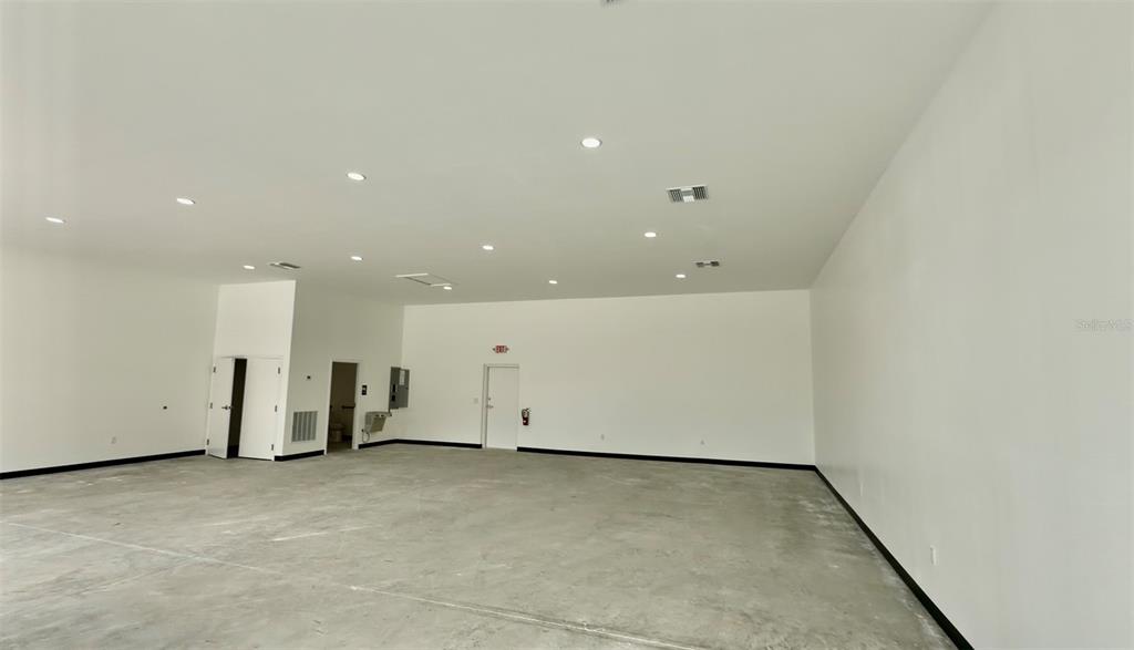 An empty, white-walled commercial space with a concrete floor and recessed ceiling lights — 727 TILLMAN PLACE UNIT 102, PLANT CITY, FL