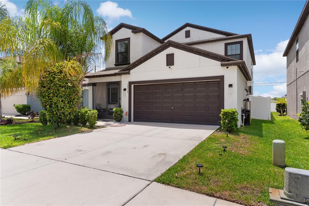 A two-story house with a white stucco exterior, brown trim, and a two-car garage — 10216 CARLOWAY HILLS DRIVE, WIMAUMA, FL