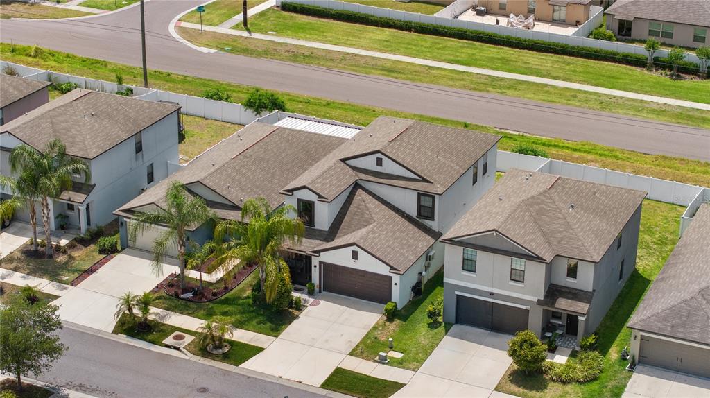 An aerial view shows three suburban houses with brown roofs and driveways in a neighborhood — 10216 CARLOWAY HILLS DRIVE, WIMAUMA, FL
