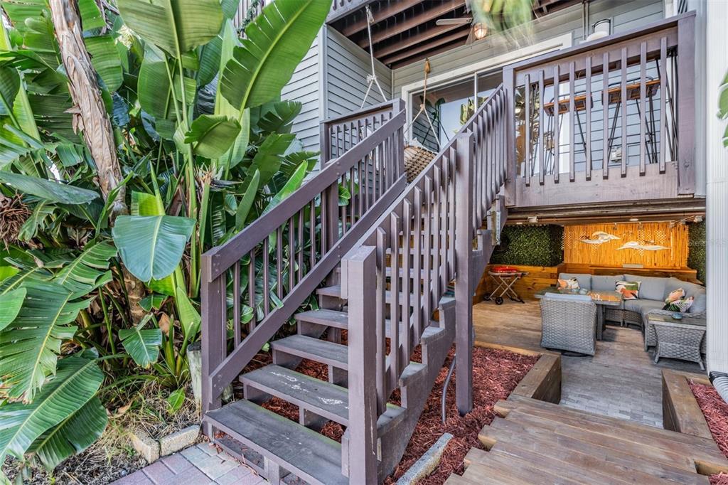 A wooden staircase leads to an elevated deck above a covered patio with outdoor seating — 200 MERES BOULEVARD UNIT 16, TARPON SPRINGS, FL