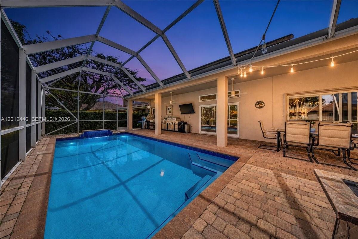 A screened-in patio features a rectangular swimming pool, brick pavers, and outdoor dining furniture — 1634 Sandpiper Cir, Weston FL 33327, WESTON, FL