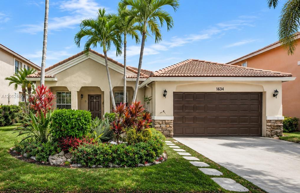 A single-story house with a brown garage, tile roof, and tropical landscaping in the front yard — 1634 Sandpiper Cir, Weston FL 33327, WESTON, FL
