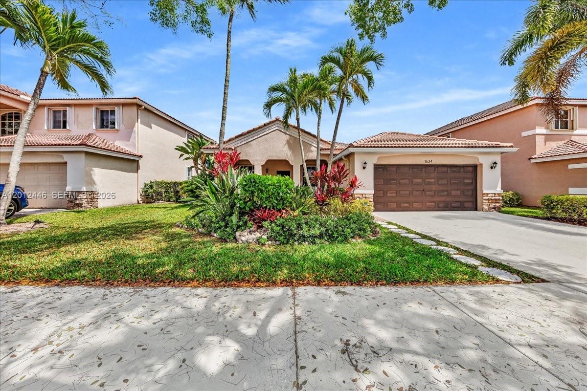 A single-story suburban house with a brown garage door and a landscaped front yard — 1634 Sandpiper Cir, Weston FL 33327, WESTON, FL