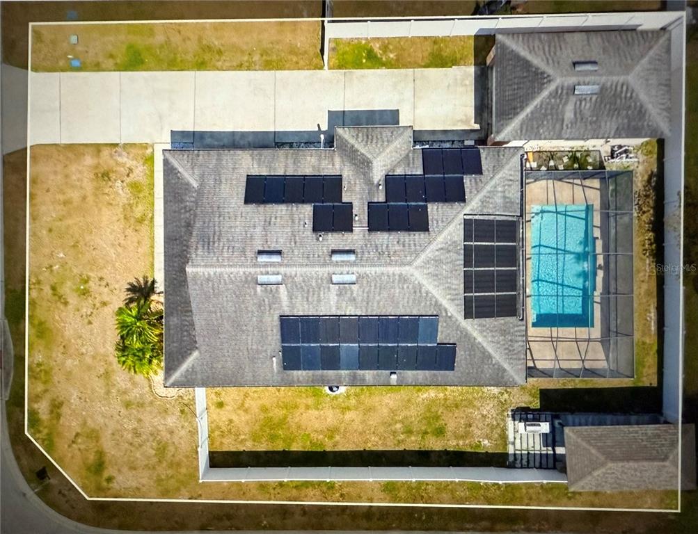 An aerial view shows a house roof with solar panels, skylights, and a screened pool — 1201 LAVENDER JEWEL COURT, PLANT CITY, FL