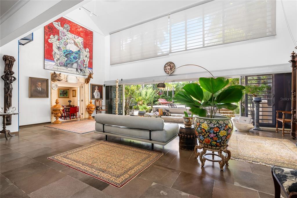 A spacious living room features high ceilings, large windows, tile floors, and eclectic art decor — 13 PEDROSA ST. GARDEN HILLS, GUAYNABO, PR