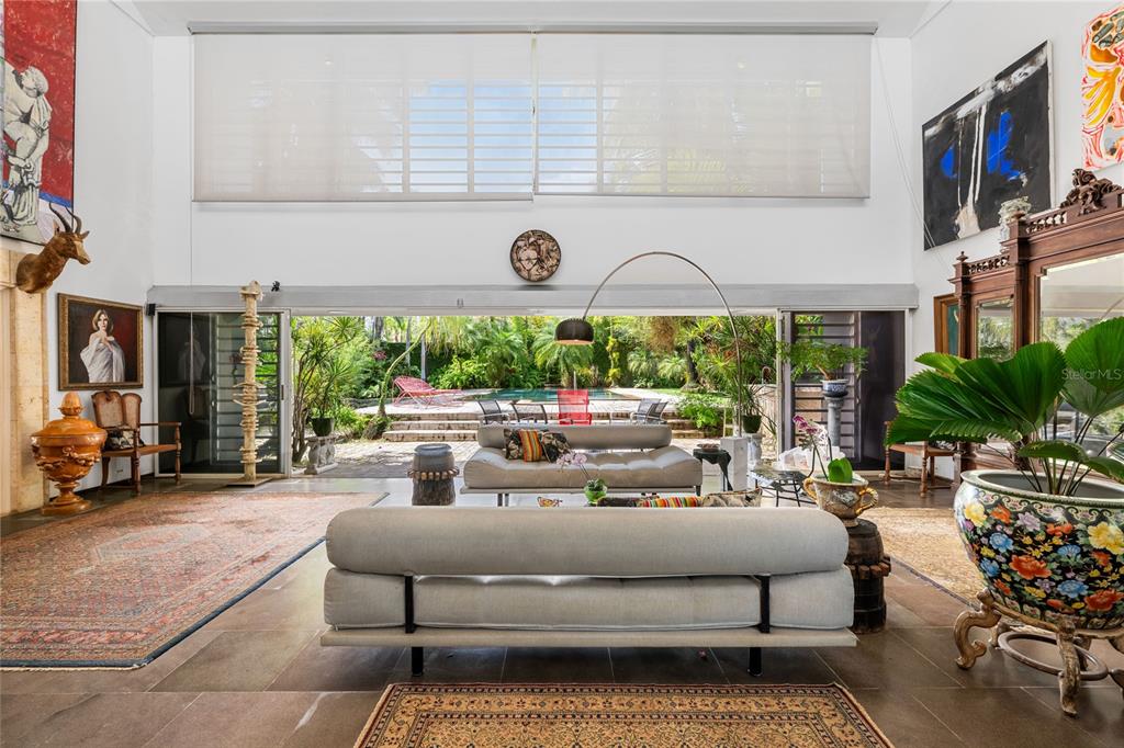 A spacious living room features two modern sofas, large sliding glass doors, and a backyard pool — 13 PEDROSA ST. GARDEN HILLS, GUAYNABO, PR