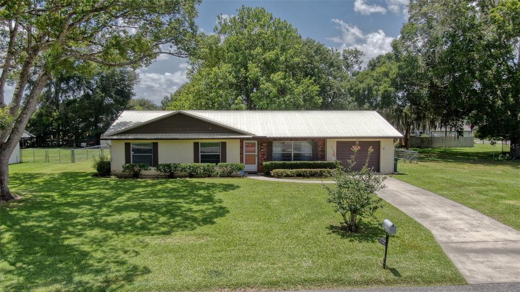 A single-story house with a metal roof, brick accents, and a concrete driveway — 4816 NE 6TH STREET, OCALA, FL