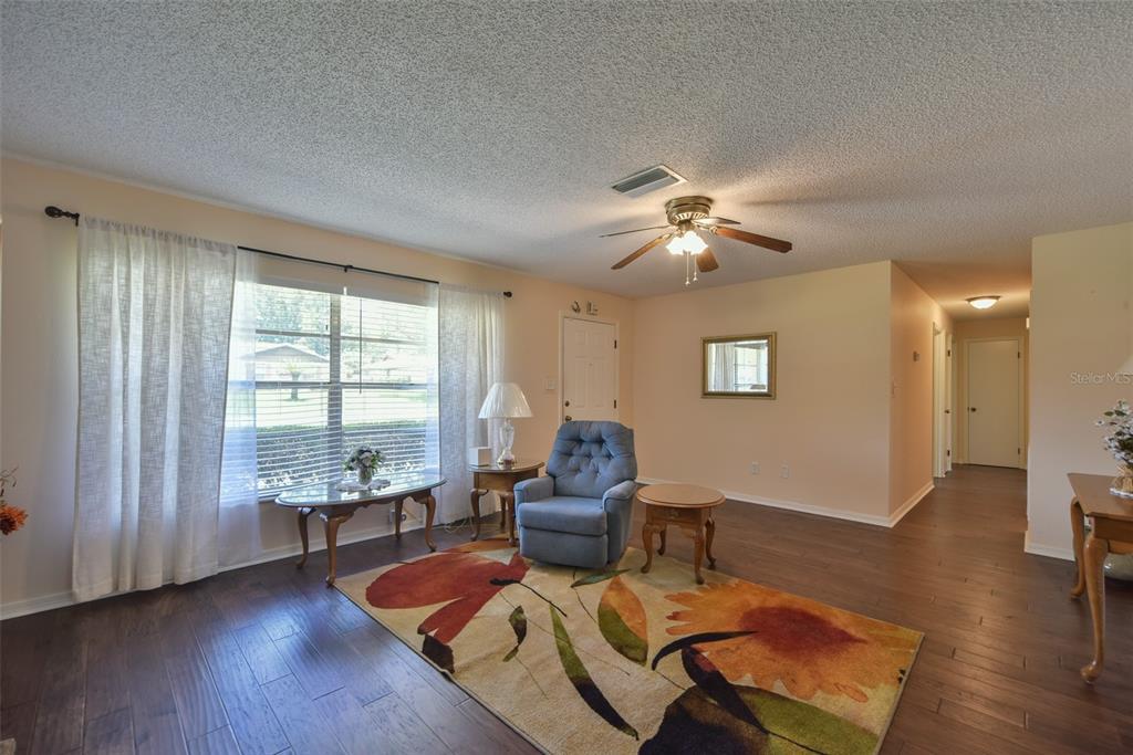 A living room features dark wood flooring, a floral area rug, and a blue armchair — 4816 NE 6TH STREET, OCALA, FL