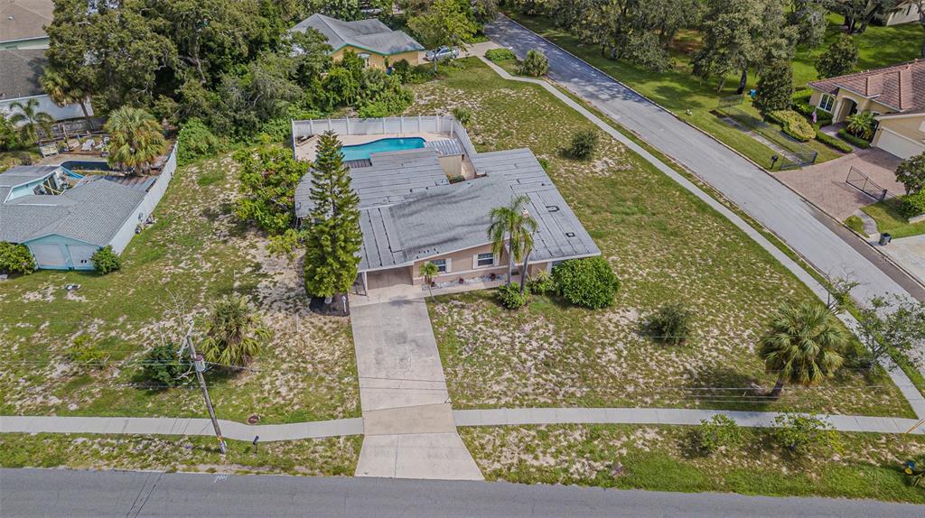 An aerial view shows a single-story house with a pool, driveway, and large yard — 912 RIVERSIDE DRIVE, TARPON SPRINGS, FL