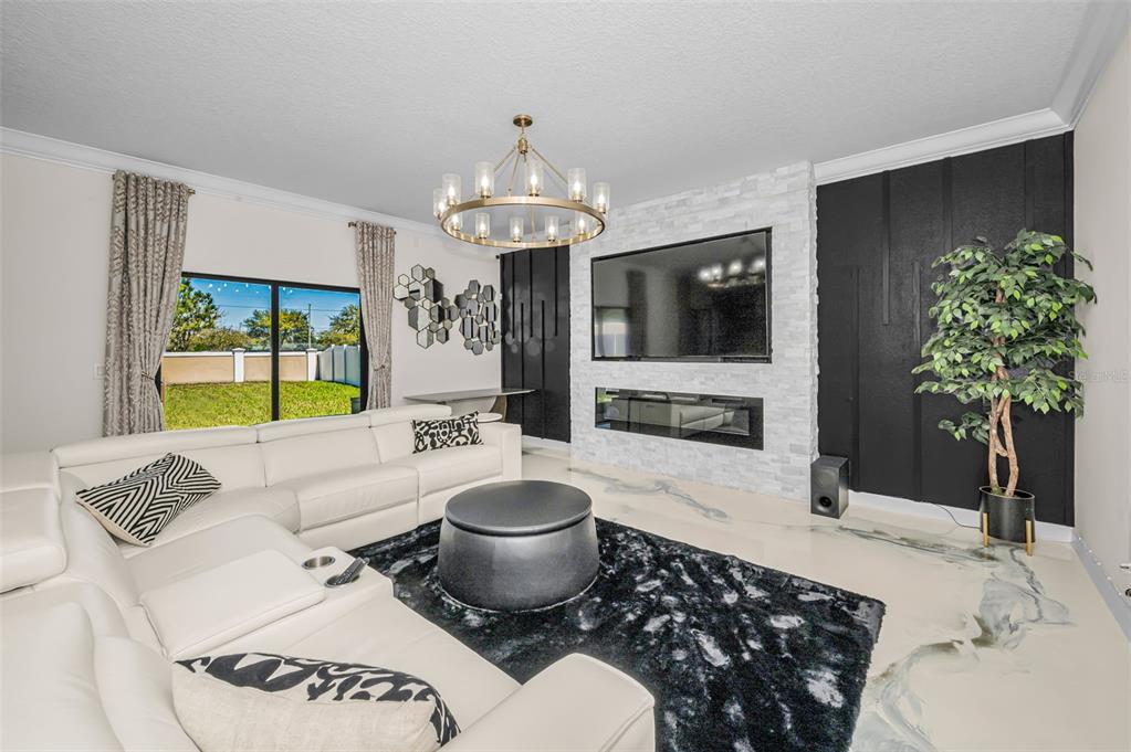 A living room features a white sectional sofa, a stone fireplace, and a black accent wall — 11922 FROST ASTER DRIVE, RIVERVIEW, FL