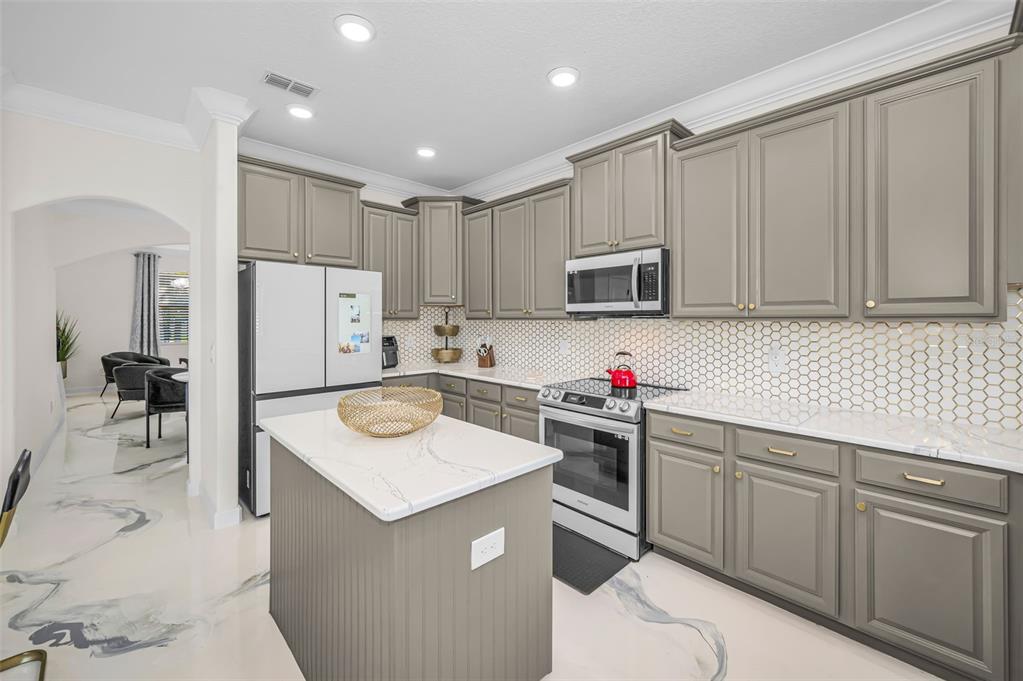 A kitchen with gray cabinets, a white marble-topped island, and a white honeycomb tile backsplash — 11922 FROST ASTER DRIVE, RIVERVIEW, FL