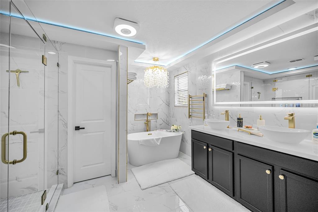 A modern bathroom features a freestanding tub, double vanity, glass shower, and marble-style tile flooring — 11922 FROST ASTER DRIVE, RIVERVIEW, FL