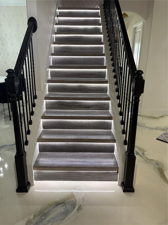 A staircase with wood-look treads, integrated LED lighting, and black metal railings — 11922 FROST ASTER DRIVE, RIVERVIEW, FL