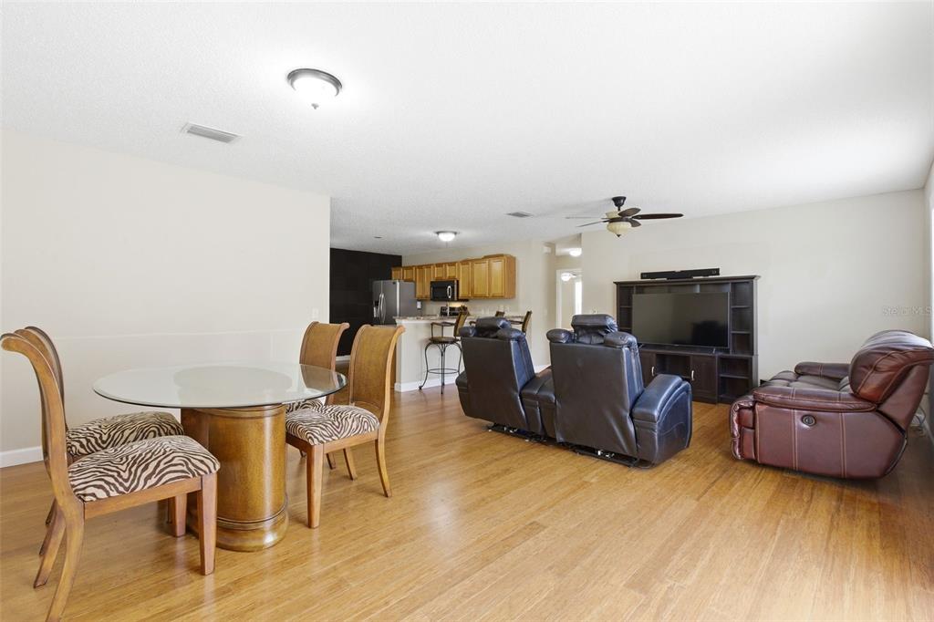 An open-concept living and dining area features wood flooring, a glass table, and leather furniture — 1671 OSPREY AVENUE, THE VILLAGES, FL