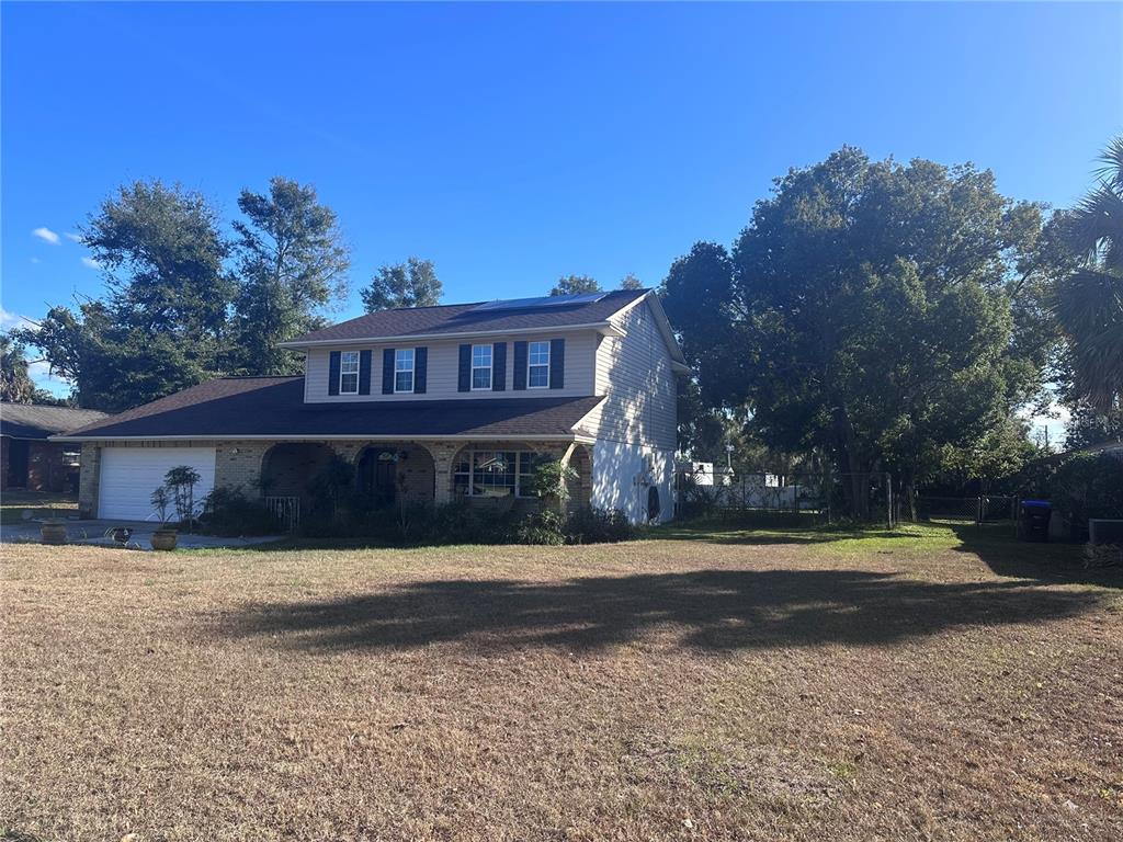 A two-story house with a brick and siding exterior stands behind a large, dry lawn — 5710 JACQULYN DRIVE, ZELLWOOD, FL