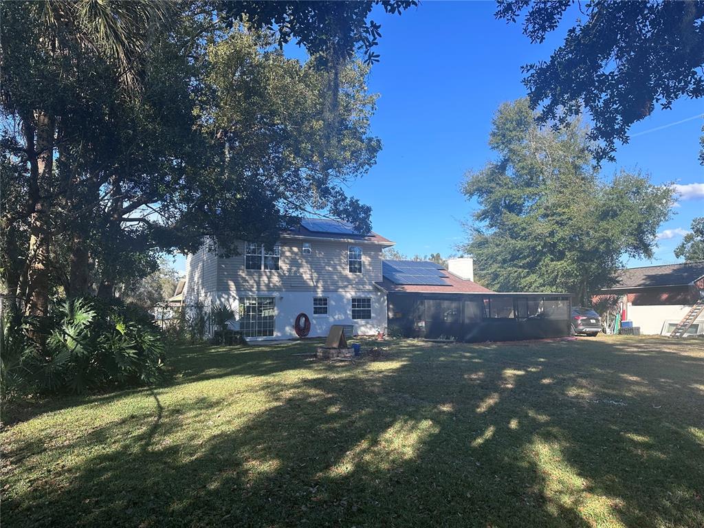 The exterior of a two-story house features solar panels on the roof and a screened-in patio — 5710 JACQULYN DRIVE, ZELLWOOD, FL