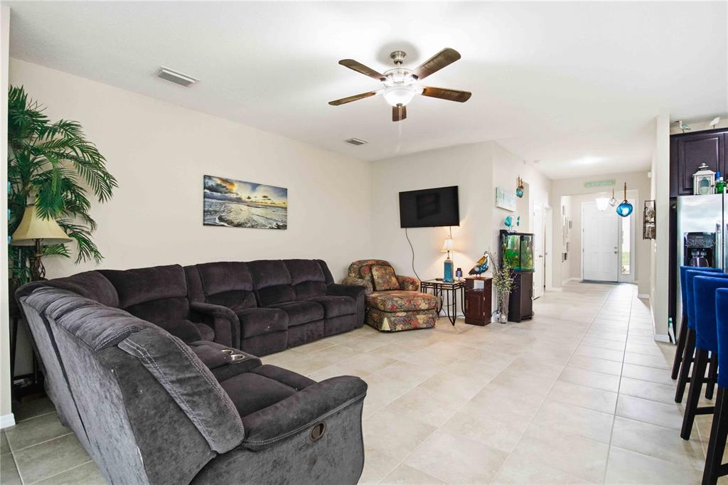 A living room features a large gray sectional sofa, a patterned armchair, and tile flooring — 444 TIERRA VERDE WAY, BRADENTON, FL