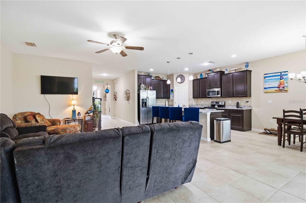 An open-concept living room and kitchen featuring dark cabinetry, tile flooring, and a ceiling fan — 444 TIERRA VERDE WAY, BRADENTON, FL
