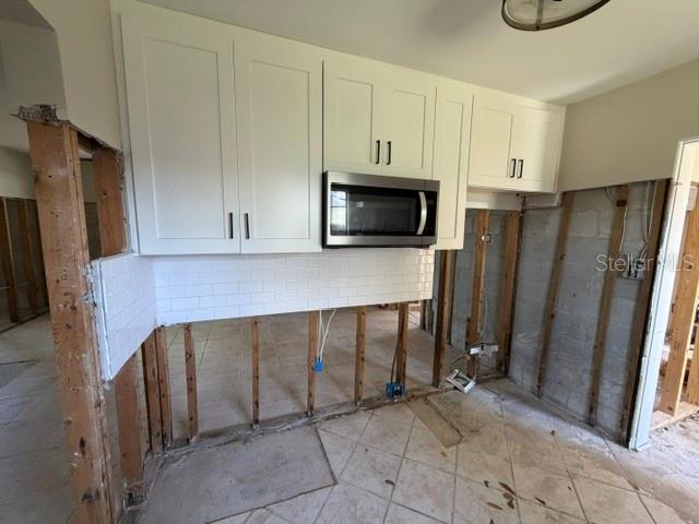 A kitchen under renovation features white upper cabinets, a microwave, and exposed wall studs — 401 PATICA ROAD NE, ST PETERSBURG, FL