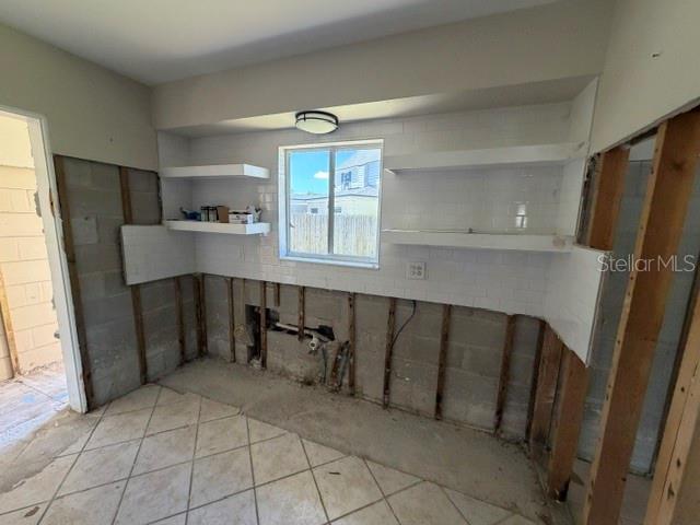 A kitchen under renovation features exposed wall studs, white subway tile, and open shelving — 401 PATICA ROAD NE, ST PETERSBURG, FL