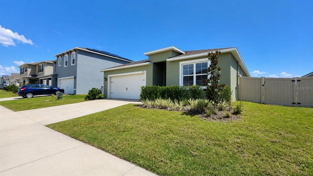 A single-story house with a green exterior, white garage door, and a tan privacy fence — 4669 BERNARD BOULEVARD, HAINES CITY, FL
