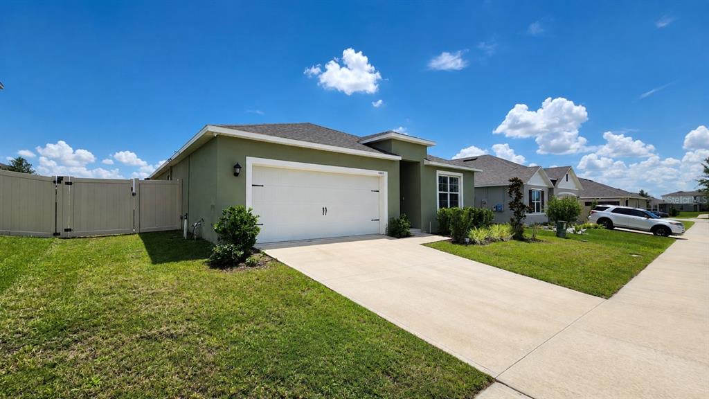 A single-story house with a green exterior, a two-car garage, and a tan vinyl fence — 4669 BERNARD BOULEVARD, HAINES CITY, FL