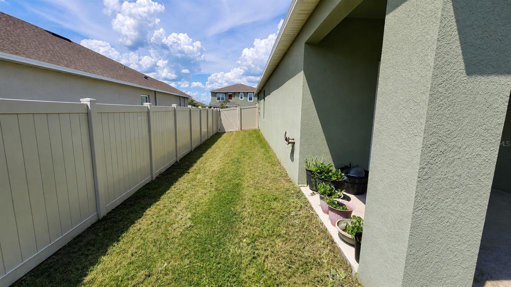 A narrow side yard features a vinyl fence, a concrete walkway, and several potted plants — 4669 BERNARD BOULEVARD, HAINES CITY, FL