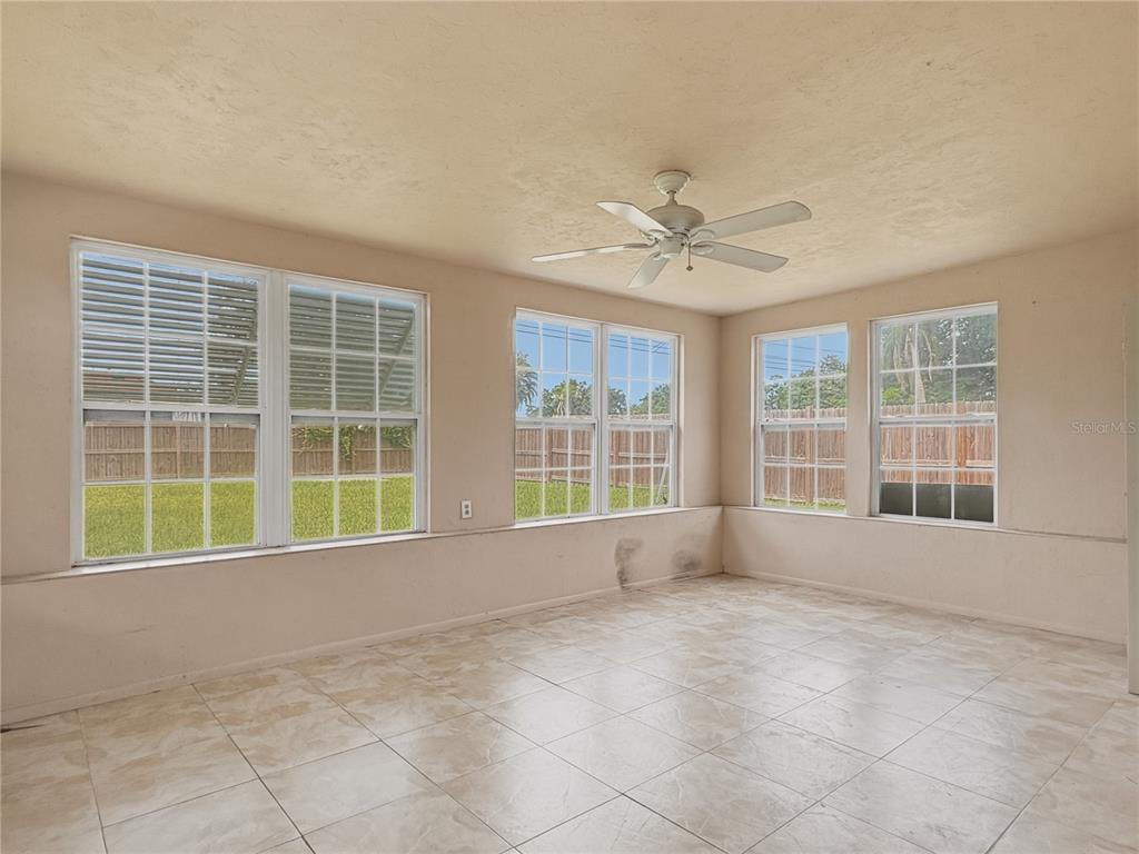 A sunroom features beige walls, tiled flooring, a ceiling fan, and multiple windows — 5430 HAYDEN BOULEVARD, SARASOTA, FL