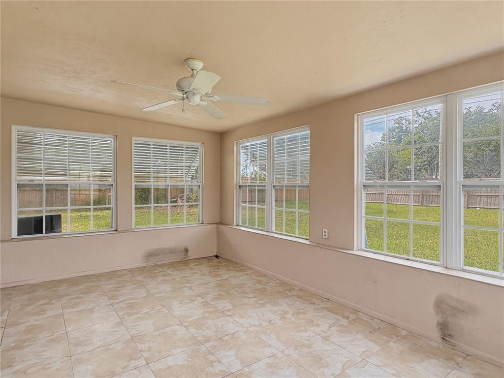A sunroom with beige tile flooring, a ceiling fan, and multiple windows overlooking a yard — 5430 HAYDEN BOULEVARD, SARASOTA, FL