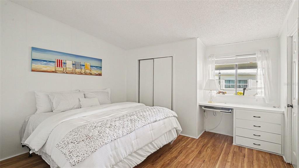A bedroom features a bed, a built-in desk with drawers, and wood-look flooring — 8430 IMPERIAL CIRCLE, PALMETTO, FL
