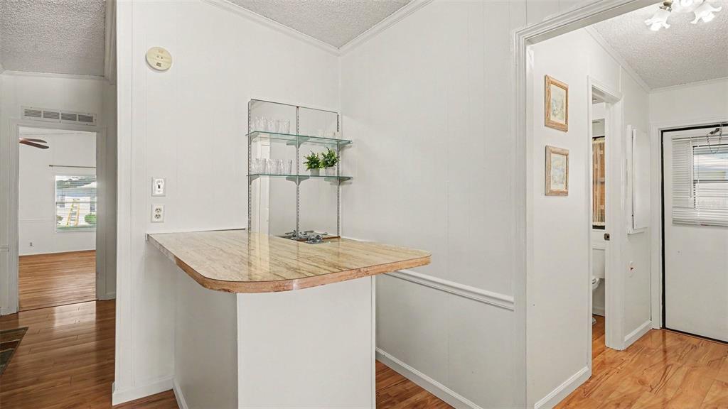 A wet bar with a laminate countertop and glass shelving sits in a white room — 8430 IMPERIAL CIRCLE, PALMETTO, FL