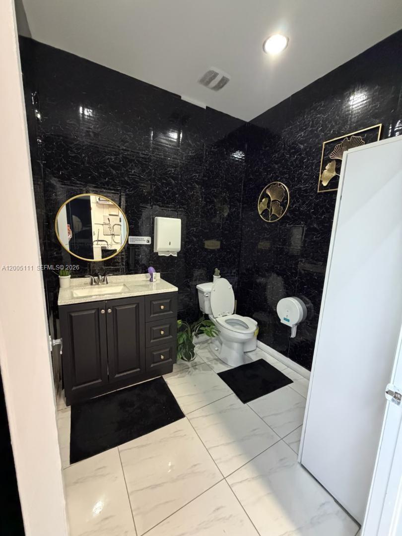A bathroom features black marble-patterned walls, a dark vanity, and white tile flooring — 8290 SW 40th St, Miami FL 33155, MIAMI, FL
