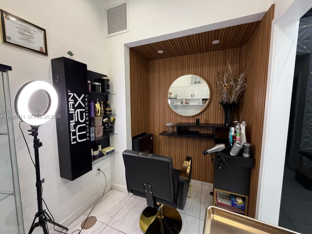 A salon station features a black chair, a circular mirror, and wood-paneled accent walls — 8290 SW 40th St, Miami FL 33155, MIAMI, FL