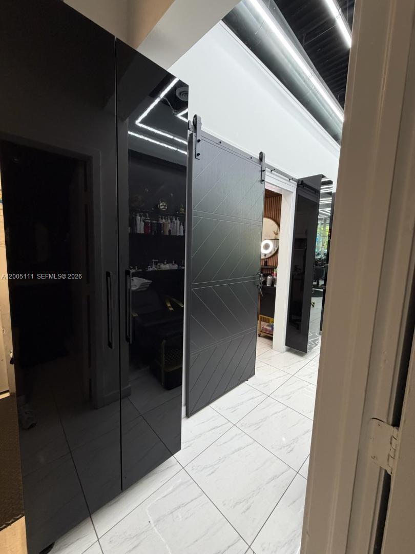 A hallway features white tiled floors, high-gloss black cabinets, and a sliding barn door — 8290 SW 40th St, Miami FL 33155, MIAMI, FL