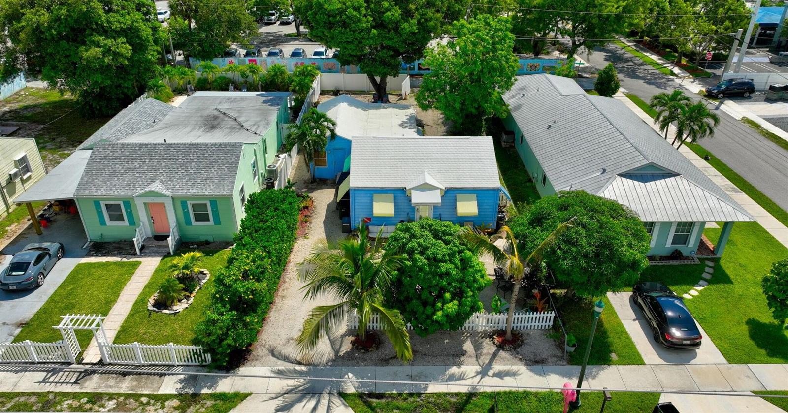 An aerial view shows three small houses with metal roofs and front lawns along a street — 629 SE 4th Avenue, Delray Beach FL 33483, DELRAY BEACH, FL